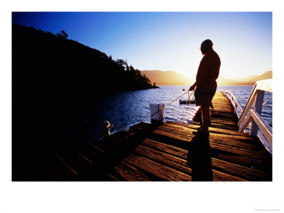 Man On Dock Silhouetted At Sunrise At Bahia Mansa, Lake Nahuel Huapi, Villa La Angostura, Argentina by Michael Taylor Pricing Limited Edition Print image