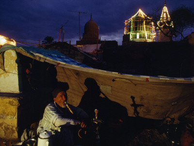 A Squatter Puffs A Water Pipe Under A Tarp In A City Cemetery by Reza Pricing Limited Edition Print image