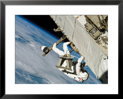 An Astronaut Mission Specialist, Crawls Along A Truss On The International Space Station by Stocktrek Images Pricing Limited Edition Print image
