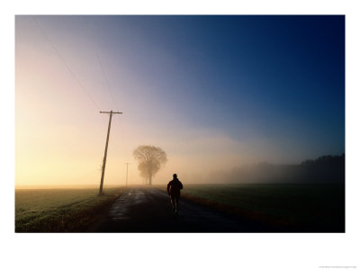 A Lone Jogger Runs Down A Rural Road In Early Morning Fog by Melissa Farlow Pricing Limited Edition Print image