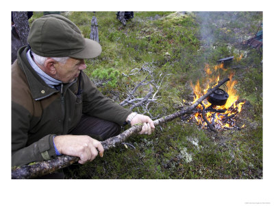Man (Aged 60 Years) Boiling Kettle Over Open Fire In Forest, Norway by Mark Hamblin Pricing Limited Edition Print image