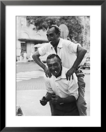 Italian Man Leaping Onto A Friend's Back In Casual Greeting While Crossing A Piazza by Paul Schutzer Pricing Limited Edition Print image