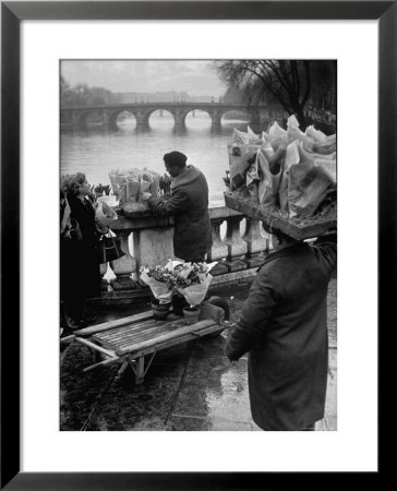 Parisian Flower Vendor At Work Stocking His Stall On The Seine With The Pont Neuf In The Background by Ed Clark Pricing Limited Edition Print image