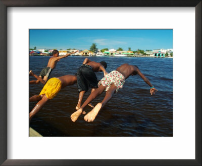 Young Boys Dive Off Marina At Bay Of Belize With City In Background, Belize City, Belize by Anthony Plummer Pricing Limited Edition Print image