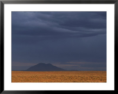 Big Southern Butte Looms In The Distance Under A Dark And Stormy Sky by Michael Melford Pricing Limited Edition Print image