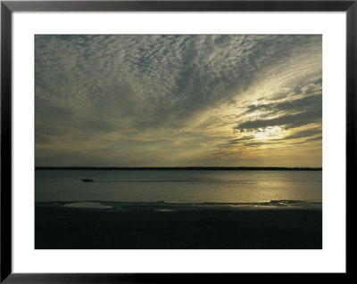 A Boat Speeds Past The Shoreline Of The Mackenzie River At Sunset by Raymond Gehman Pricing Limited Edition Print image
