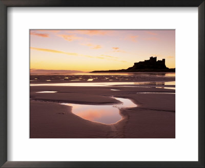 Bamburgh Castle In Silhouette At Sunrise, With Rock Pools On Empty Beach, Northumberland, England by Lee Frost Pricing Limited Edition Print image