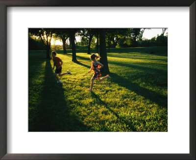 Backlit View Of Children Running Through A Glade Of Trees by Joel Sartore Pricing Limited Edition Print image