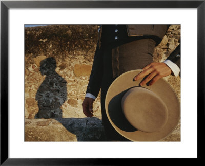 A Man In Traditional Dress Casts A Shadow Against A Stone Wall by Raul Touzon Pricing Limited Edition Print image