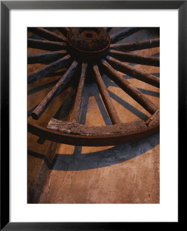 Close-Up Of Wooden Wagon Wheel Lit By Setting Sun by Todd Gipstein Pricing Limited Edition Print image