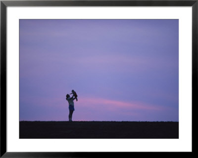 A Mother Holding Up Her Baby Sihouetted Against A Sky At Sunset by Joel Sartore Pricing Limited Edition Print image
