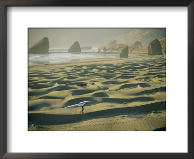 A Windsurfer Walks Across The Sand Dunes Near The Rocky Coastline by Skip Brown Pricing Limited Edition Print image