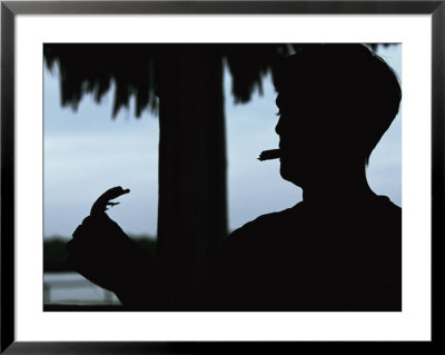A Cigar-Smoking Cuban Man In Silhouette Holds A Baby Crocodile by Steve Winter Pricing Limited Edition Print image