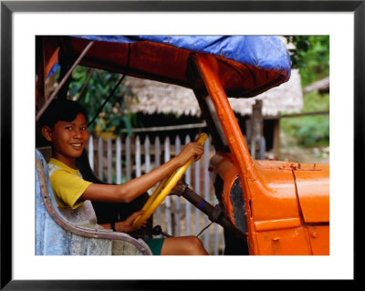 Boy Pretending To Drive Truck In Mrauk-U Village, Looking At Camera, Mrauk U, Myanmar (Burma) by Corey Wise Pricing Limited Edition Print image