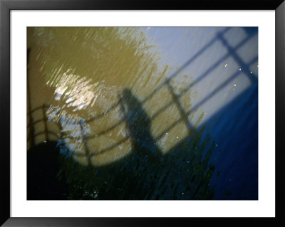 Shadow Of A Person Walking Across Bridge On Canal Water, Amsterdam, Netherlands by Martin Moos Pricing Limited Edition Print image