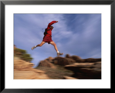 A Runner Leaps Across Rocks In Moab, Utah by Bill Hatcher Pricing Limited Edition Print image