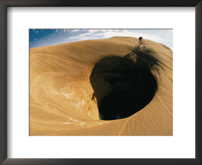 A Mountain Biker Cycles Around A Spectacular Crater In The Desert by Dugald Bremner Pricing Limited Edition Print image