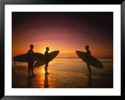 Three Surfers Hold Surfboards On Beach At Sunset by Doug Mazell Pricing Limited Edition Print image