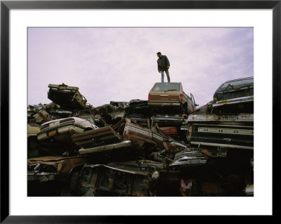 A Man Stands Atop A Pile Of Crushed Cars At A Salvage Yard by Joel Sartore Pricing Limited Edition Print image