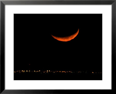 A Crescent Moon Dwarfs The Lights Of Fort Riley Army Base In Central Kansas, January 22, 2007 by Charlie Riedel Pricing Limited Edition Print image