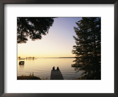 A Silhouetted Couple Sitting On The End Of A Pier At Sunset by Michael S. Lewis Pricing Limited Edition Print image