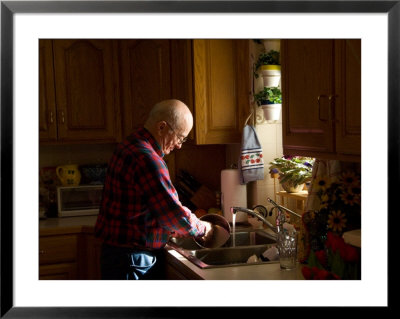Sun Shines Down On An Older Male Washing Dishes In His Home by Joel Sartore Pricing Limited Edition Print image