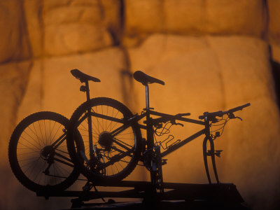 Silhouette Of Mountain Bikes On A Car Roof Rack At Sunset by Images Monsoon Pricing Limited Edition Print image