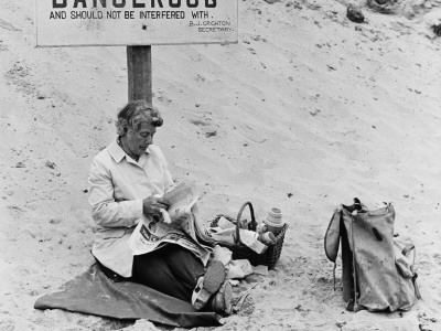 Funny Picture Of Lady On Beach Under 'Dangerous' Sign by Shirley Baker Pricing Limited Edition Print image