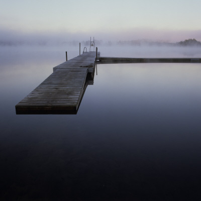 A Wooden Wharf On Still Water In Misty Weather by Mikael Andersson Pricing Limited Edition Print image