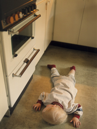 High Angle View Of A Baby Boy Lying On The Floor In A Domestic Kitchen by Bosse Kinnas Pricing Limited Edition Print image
