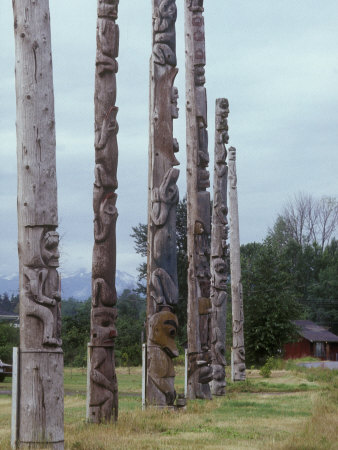 Six Wooden Totem Poles Stand In A Row In Kitwanga, British Columbia by Stephen Sharnoff Pricing Limited Edition Print image