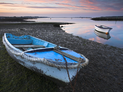 Small Boats In Poole Harbour At Dawn, One Pulled Up On The Muddy Beach. Dorset, England by Adam Burton Pricing Limited Edition Print image