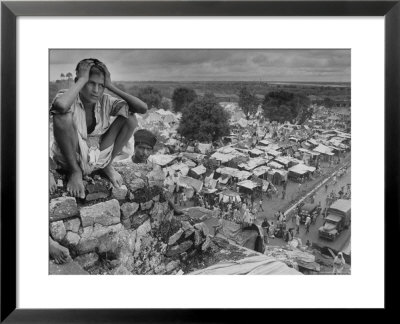 Boy Sitting On Rock Ledge Above Refugee Camp by Margaret Bourke-White Pricing Limited Edition Print image