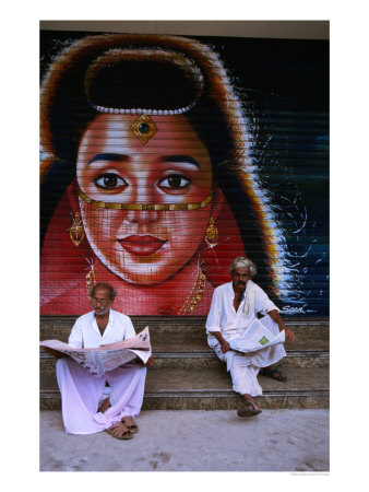 Local Men Read Newspapers In Front Of Painted Shutter, Kozhikode, Kerala, India by Greg Elms Pricing Limited Edition Print image