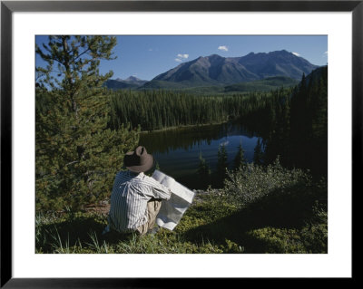 A Man With A Cowboy Hat Reads A Map And Gazes Across A River by Raymond Gehman Pricing Limited Edition Print image