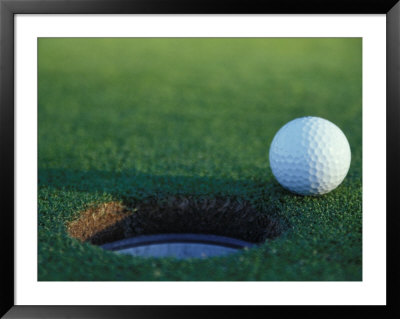 Golf Ball Poised At Edge Of Hole by Fogstock Llc Pricing Limited Edition Print image