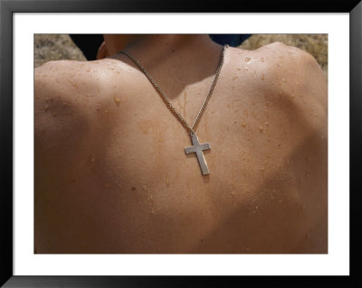A Silver Crucifix Hangs From A Chain On The Back Of A Shirtless Boy by Randy Olson Pricing Limited Edition Print image