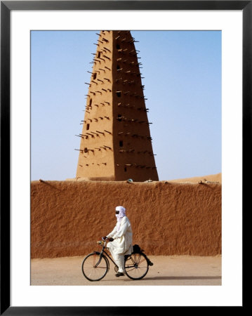 Robed Tuareg Man Cycling Past Minaret Of Mud-Brick Grande Mosquee, Agadez, Niger by Pershouse Craig Pricing Limited Edition Print image