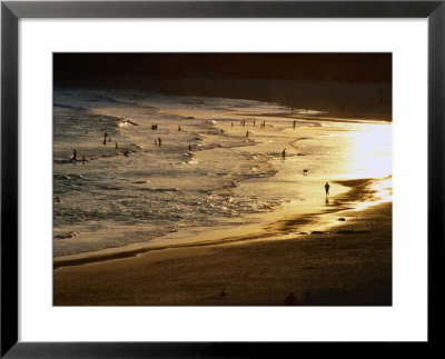 The Setting Sun Illuminates Surfers And Swimmers On Bondi Beach, Sydney, Australia by Glenn Beanland Pricing Limited Edition Print image