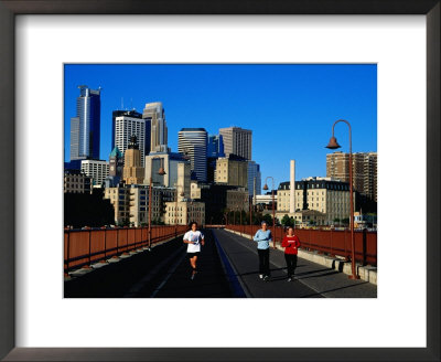 Women Jogging Across Stone Arch Bridge With City Skyline Beyond, Minneapolis, Usa by Richard Cummins Pricing Limited Edition Print image