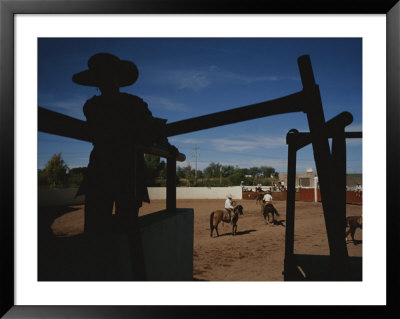 A Silhouetted Cowboy Watches Riders In A Ring by Raul Touzon Pricing Limited Edition Print image