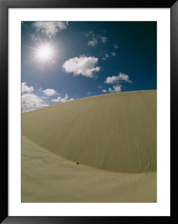 Sunlight And Puffy Clouds Over Huge Sand Dunes With Animal Tracks by Wolcott Henry Pricing Limited Edition Print image