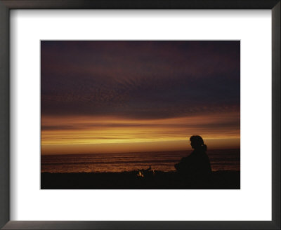 Woman Sitting By Campfire On The Beach At Sunset by Todd Gipstein Pricing Limited Edition Print image