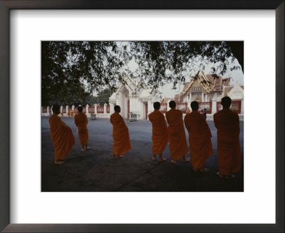 Buddhist Monks In Orange Robes Stand Outside An Ornate Building by Jodi Cobb Pricing Limited Edition Print image