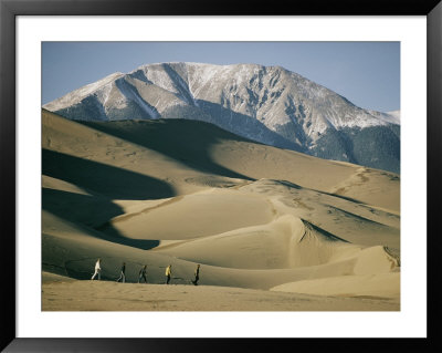 Hikers Among The Sand Dunes With A Snow-Covered Mountain Rising In The Background by Walter Meayers Edwards Pricing Limited Edition Print image