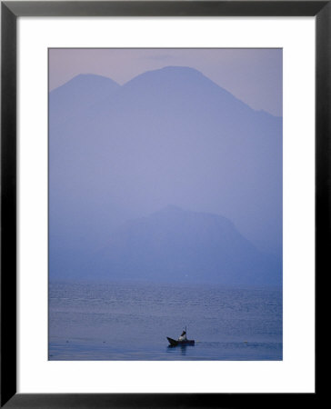 A Lone Boat Plies A Mountain Lake In Early Morning Fog by Raul Touzon Pricing Limited Edition Print image