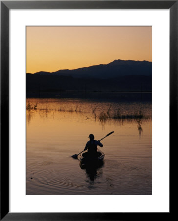 A Boater Paddles On Mystic Lake At Twilight by Phil Schermeister Pricing Limited Edition Print image