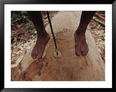 A Man Drills Shallow Holes Into The Bottom Of A Log To Guide Workers by Nicolas Reynard Pricing Limited Edition Print image