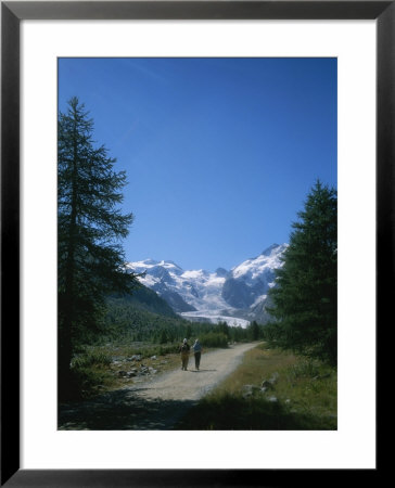 A Couple Walks Toward The Morteratsch Glacier In Switzerland by Taylor S. Kennedy Pricing Limited Edition Print image