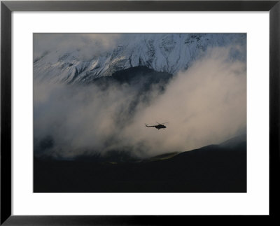 A Silhouetted Helicopter Flies Over A Smoldering Crater by Peter Carsten Pricing Limited Edition Print image